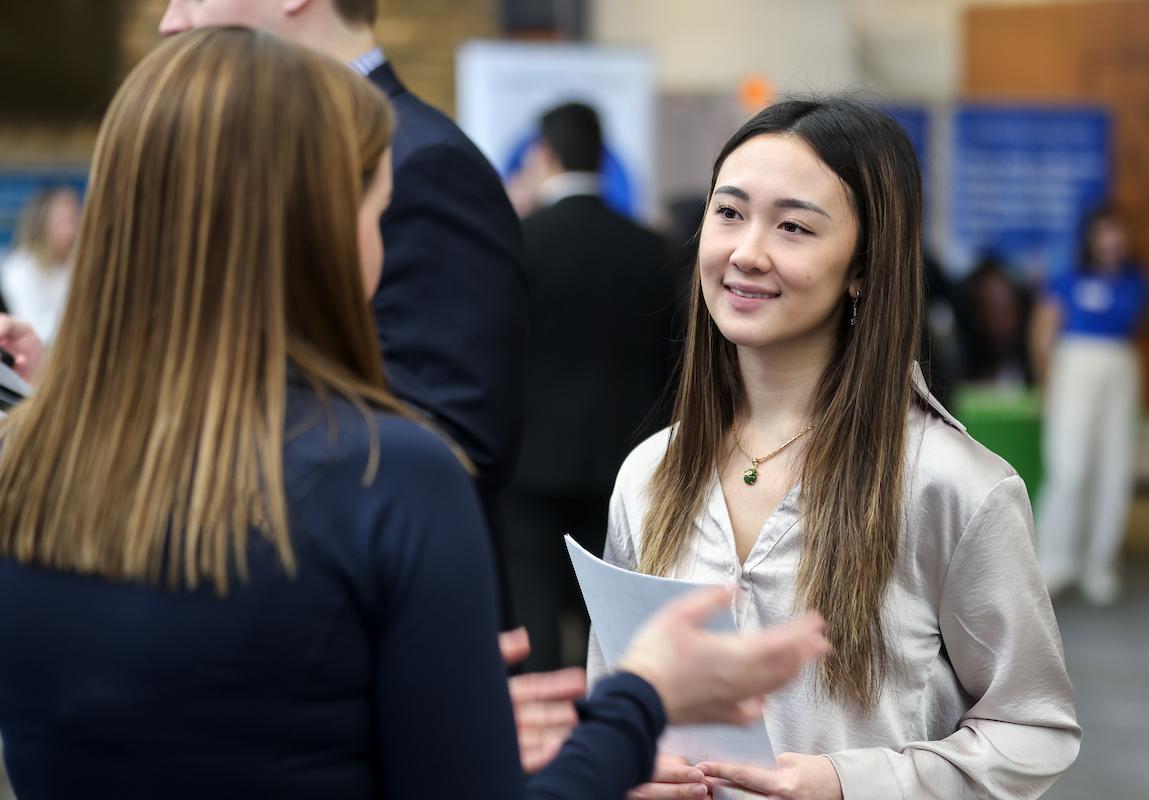 Student with resume listening attentively to corporate recruiter at the Carlson School Career Fair.